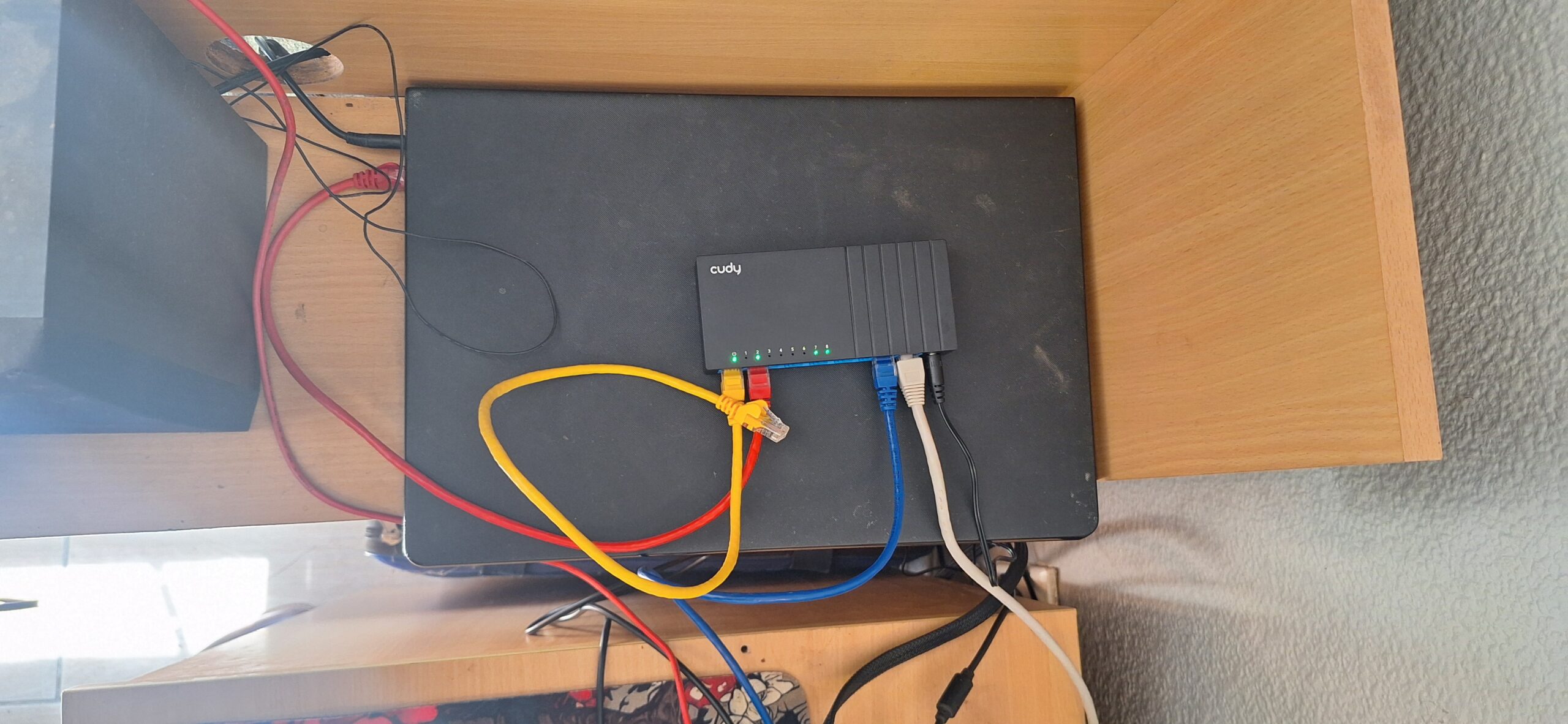 Cudy GS108D 8-port gigabit switch sitting on top of Shiro with coloured ethernet cables plugged in